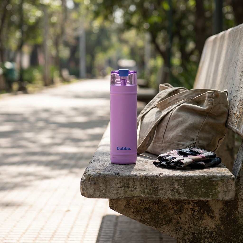A lifestyle image of the bubba DualSip and water bottle with moodbooster lilac on a concrete park bench, with a blurred natural background.
